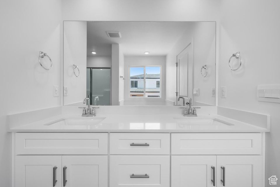 Full bath featuring double vanity and a shower stall