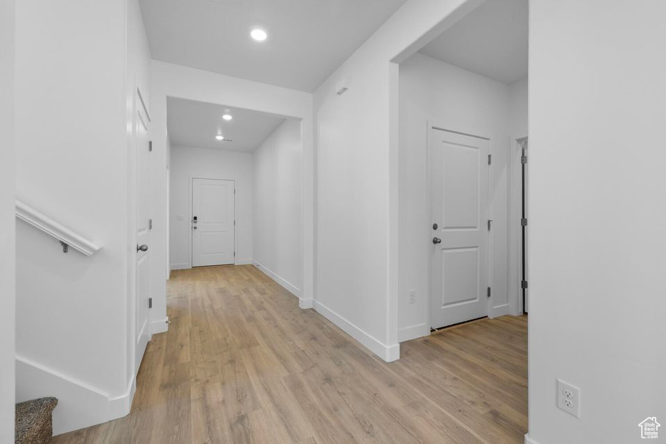 Hallway with light wood-style flooring, recessed lighting, and stairway