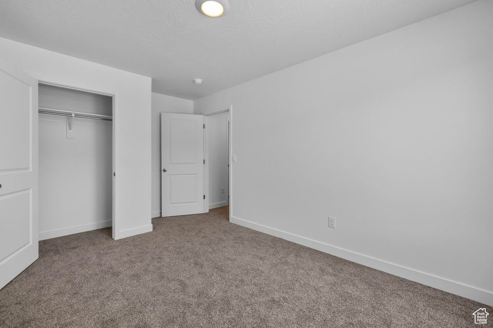 Unfurnished bedroom featuring carpet and a closet