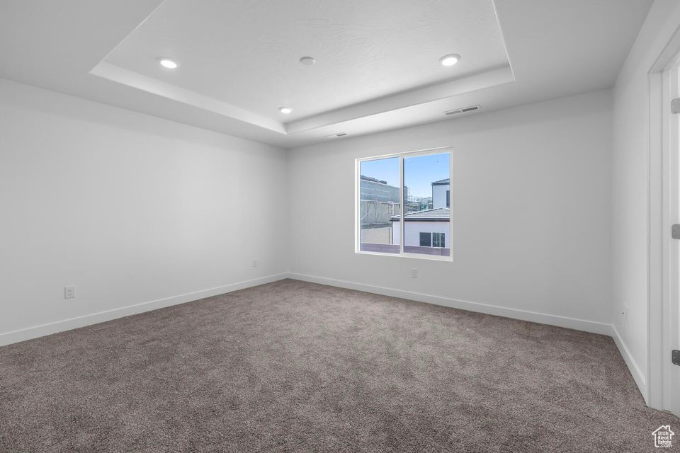 Unfurnished room featuring a raised ceiling, carpet floors, and recessed lighting