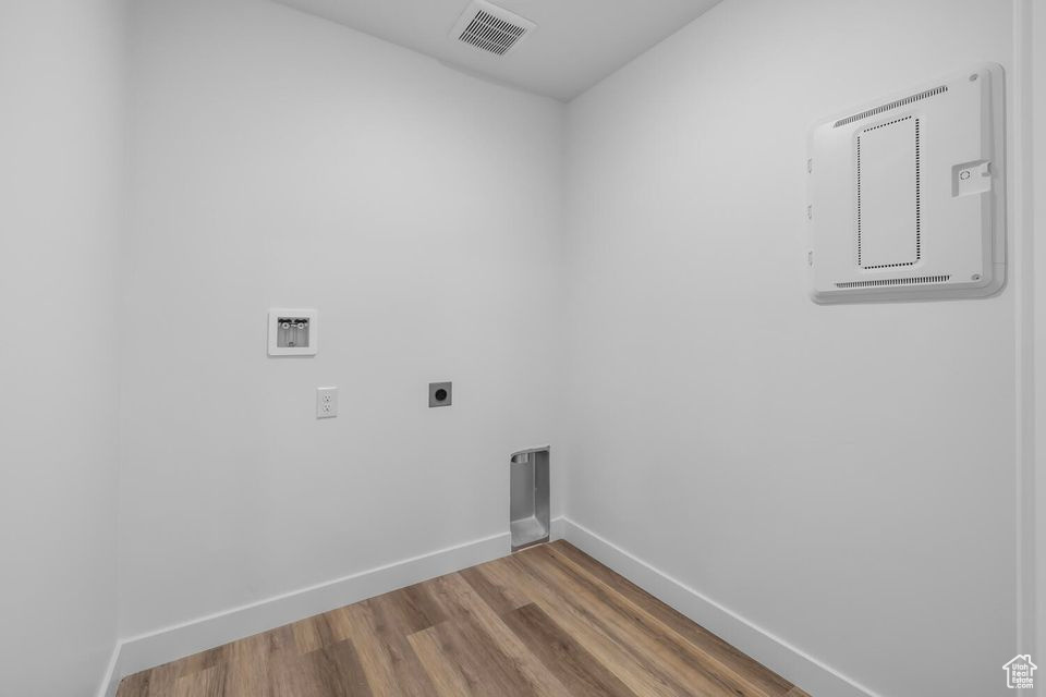 Laundry area with hookup for an electric dryer, wood finished floors, and hookup for a washing machine