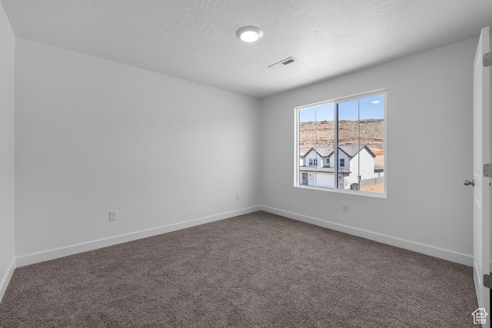Carpeted empty room featuring baseboards and a textured ceiling