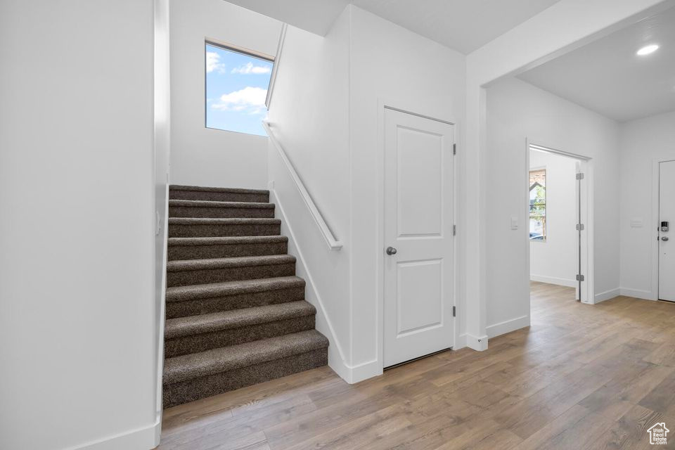Stairway featuring wood finished floors and recessed lighting