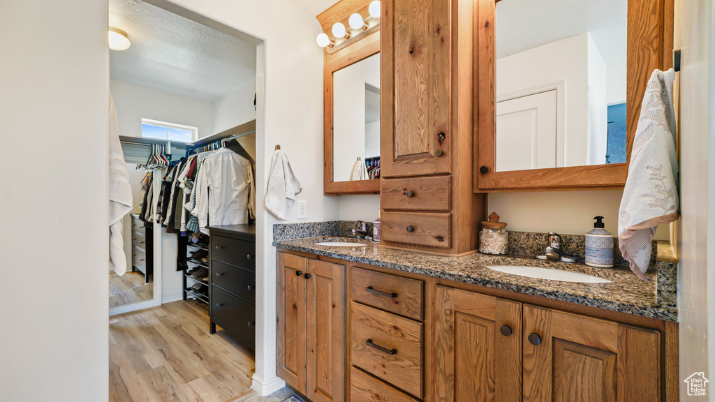 Bathroom featuring double vanity, wood finished floors, and a walk in closet