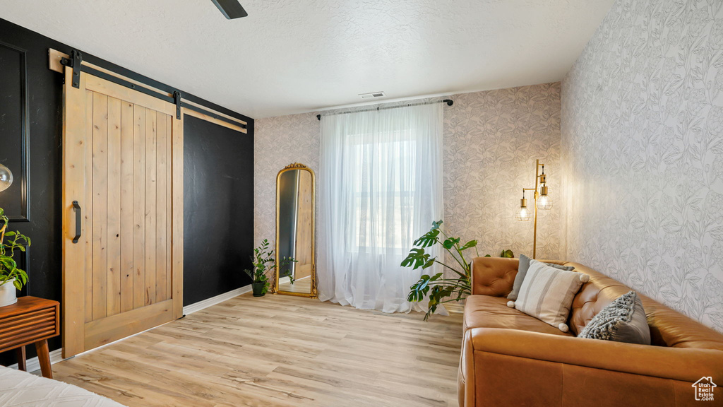 Living area featuring a barn door, light wood-style floors, and wallpapered walls