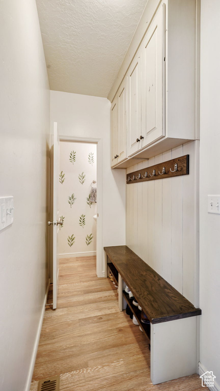 Mudroom with light wood-type flooring and a textured ceiling