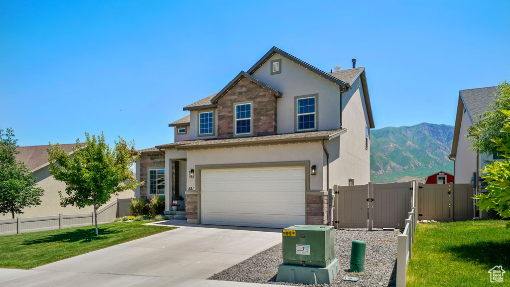 Traditional-style house with a gate, stucco siding, stone siding, an attached garage, and driveway