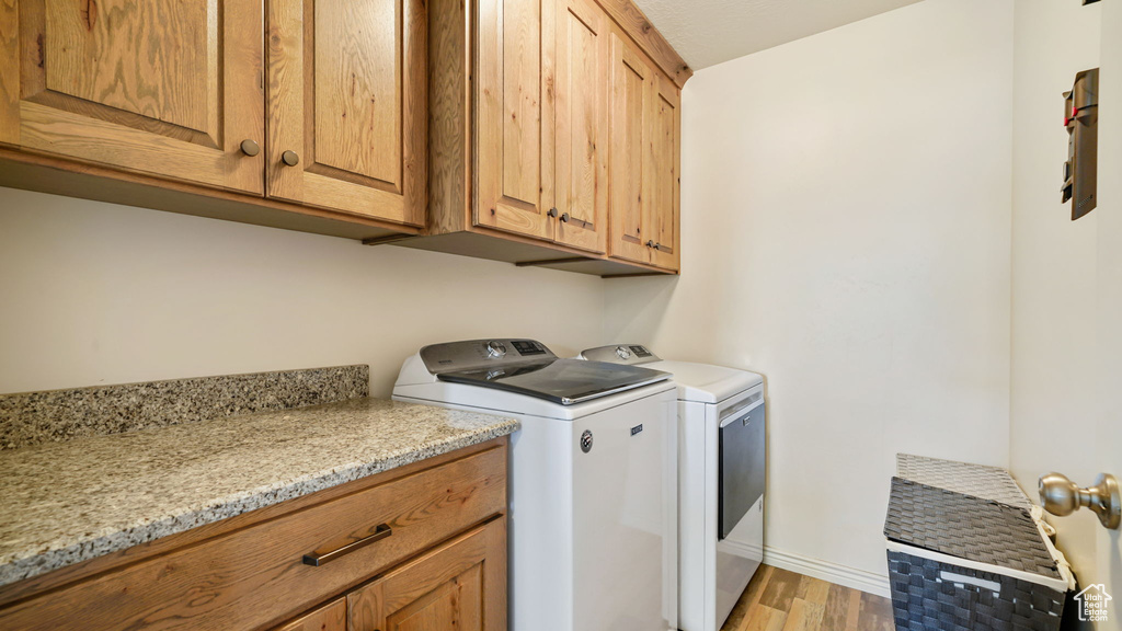Washroom with washing machine and dryer, cabinet space, and light wood-style floors