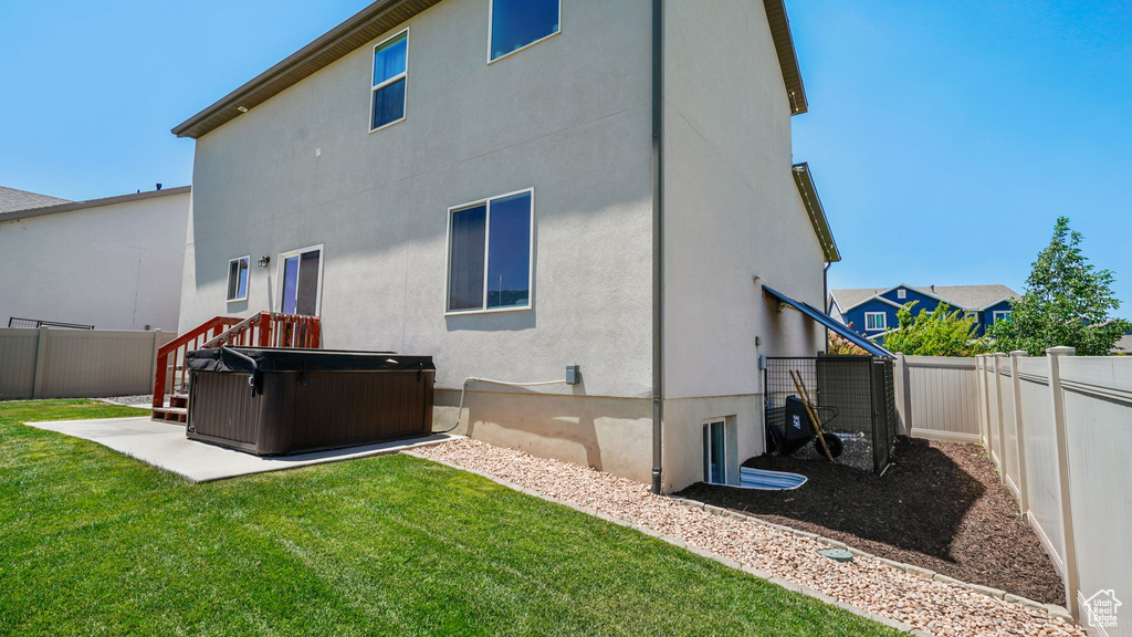 Back of house with a hot tub, a fenced backyard, a patio, and stucco siding