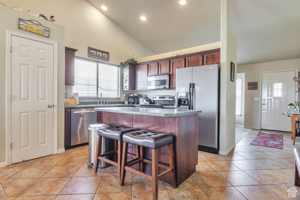 Kitchen featuring stainless steel appliances, a center island, recessed lighting, high vaulted ceiling, and a kitchen breakfast bar