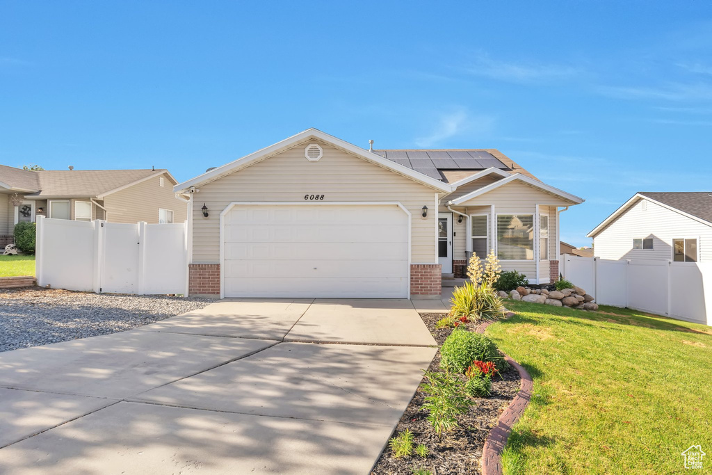 View of front of house with brick siding, solar panels, driveway, and a garage