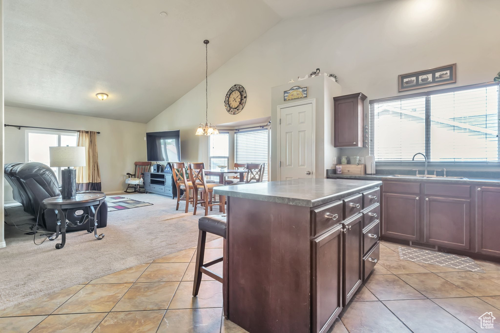Kitchen featuring high vaulted ceiling, light tile patterned floors, light carpet, healthy amount of natural light, and open floor plan