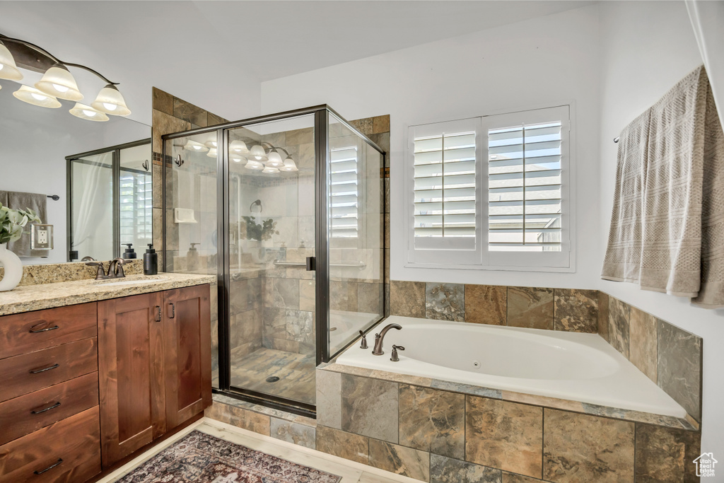 Full bathroom featuring vanity, a jetted tub, and a stall shower