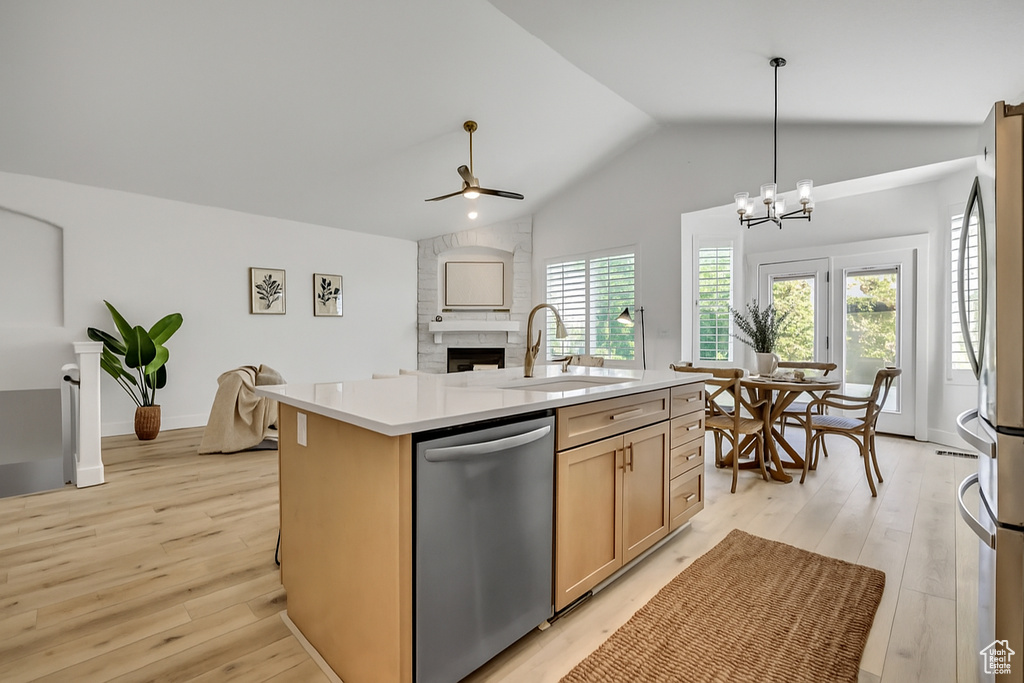 Kitchen featuring appliances with stainless steel finishes, lofted ceiling, light wood-style flooring, a ceiling fan, and a fireplace