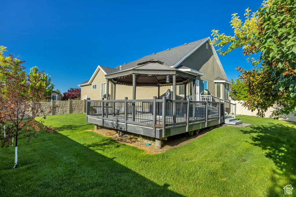Back of house with a gazebo, stucco siding, a fenced backyard, and a wooden deck