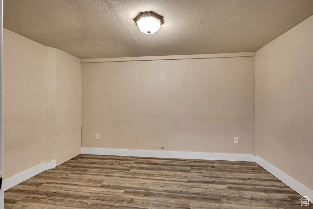 Empty room with wood finished floors and a textured ceiling