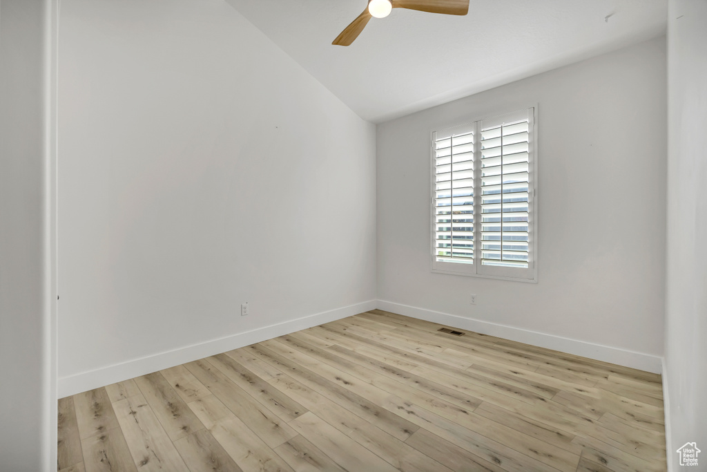 Empty room featuring lofted ceiling, ceiling fan, and wood finished floors