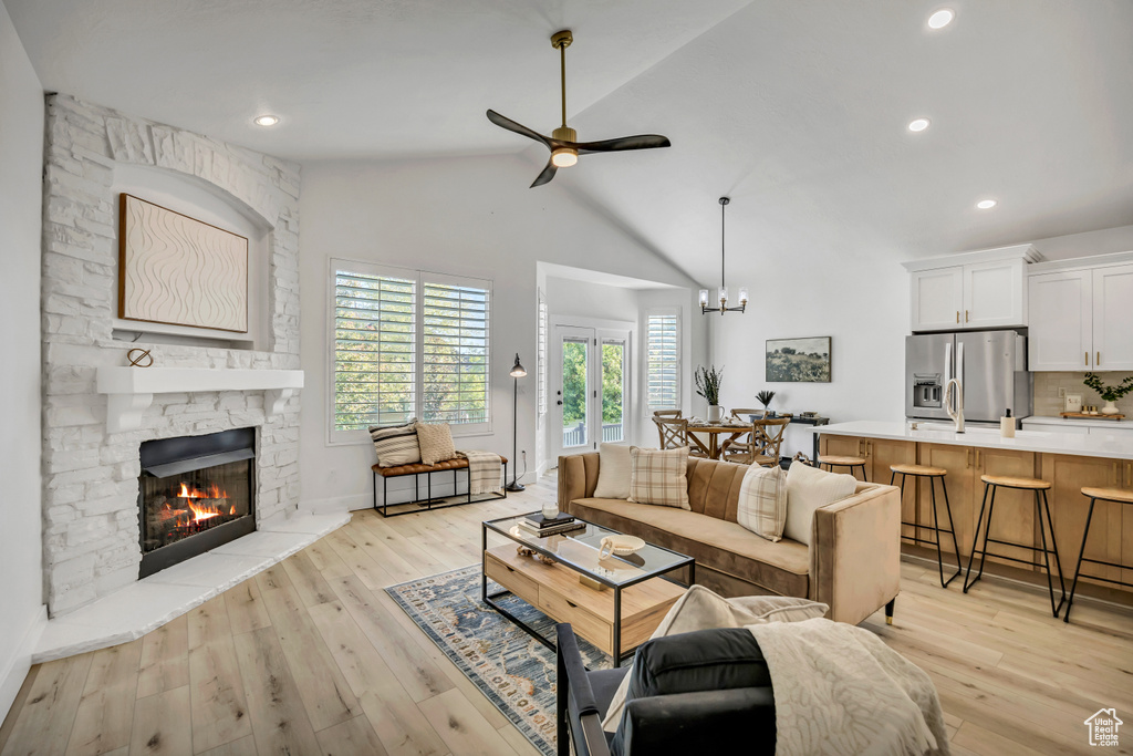 Living room featuring a fireplace, ceiling fan, light wood finished floors, high vaulted ceiling, and recessed lighting