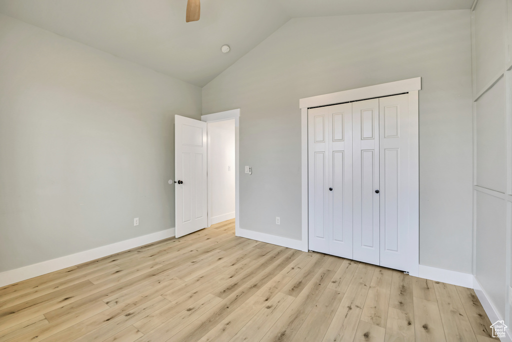 Unfurnished bedroom featuring high vaulted ceiling, light wood-style flooring, a ceiling fan, and a closet