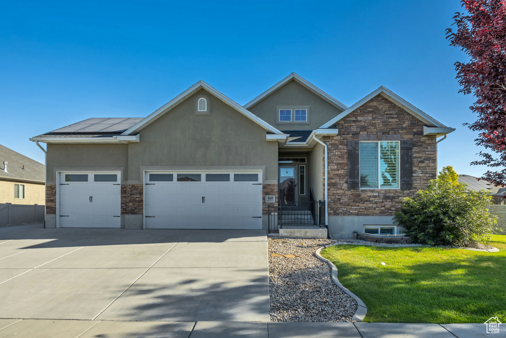 View of front of house with stone siding, stucco siding, concrete driveway, and a garage
