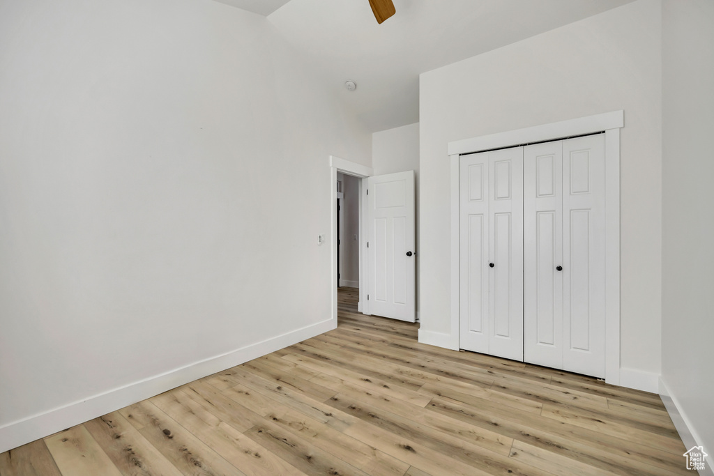 Unfurnished bedroom featuring wood finished floors, a closet, and high vaulted ceiling