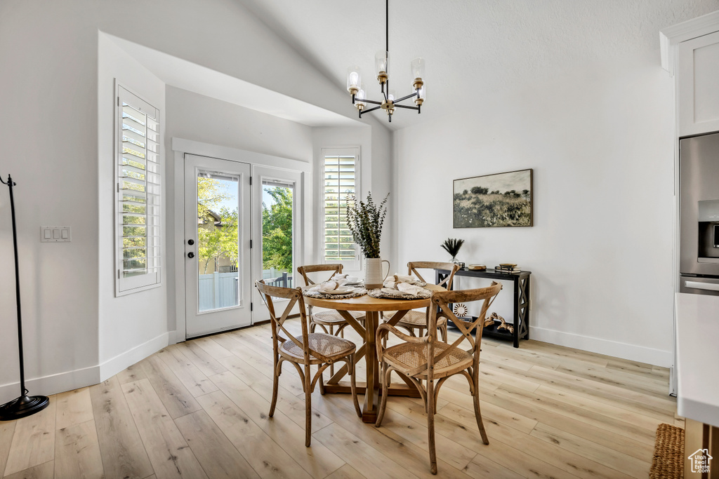 Dining room with a chandelier, light wood finished floors, and lofted ceiling