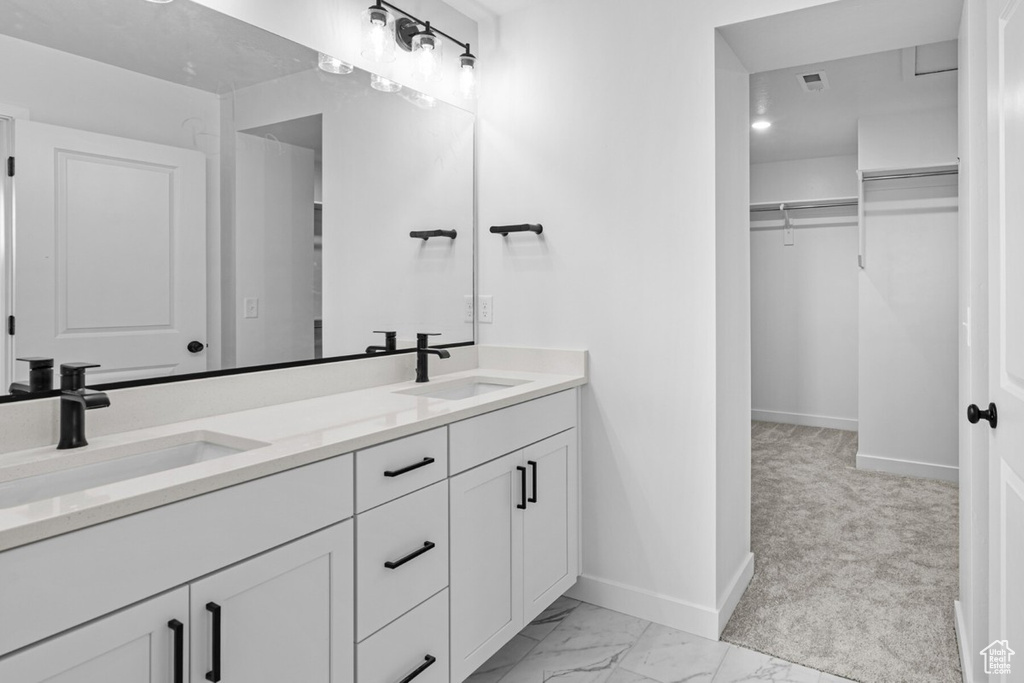 Full bathroom with double vanity, a spacious closet, and marble look tiles