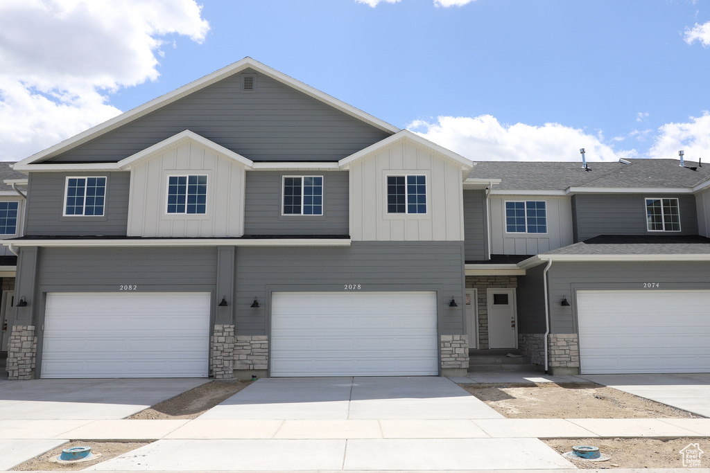 Townhome / multi-family property featuring stone siding, board and batten siding, and a garage