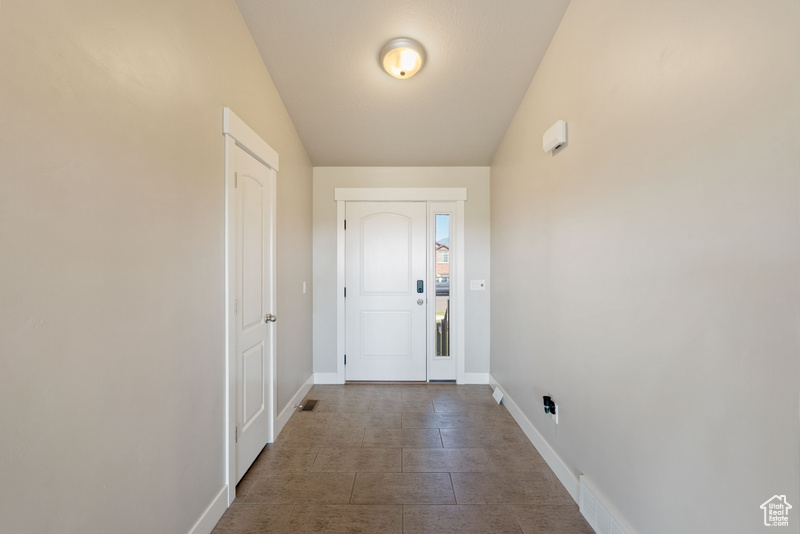Entryway with baseboards and dark tile patterned floors