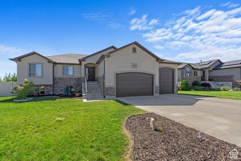 View of front of property with an attached garage, stucco siding, driveway, and stone siding