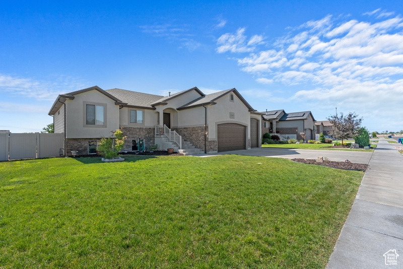 View of front facade with driveway, stucco siding, and stone siding