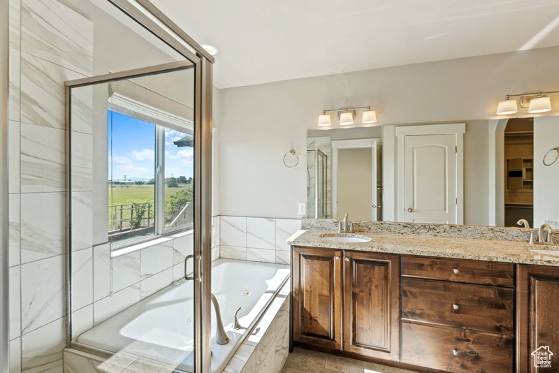 Full bathroom with a jetted tub, double vanity, and a stall shower