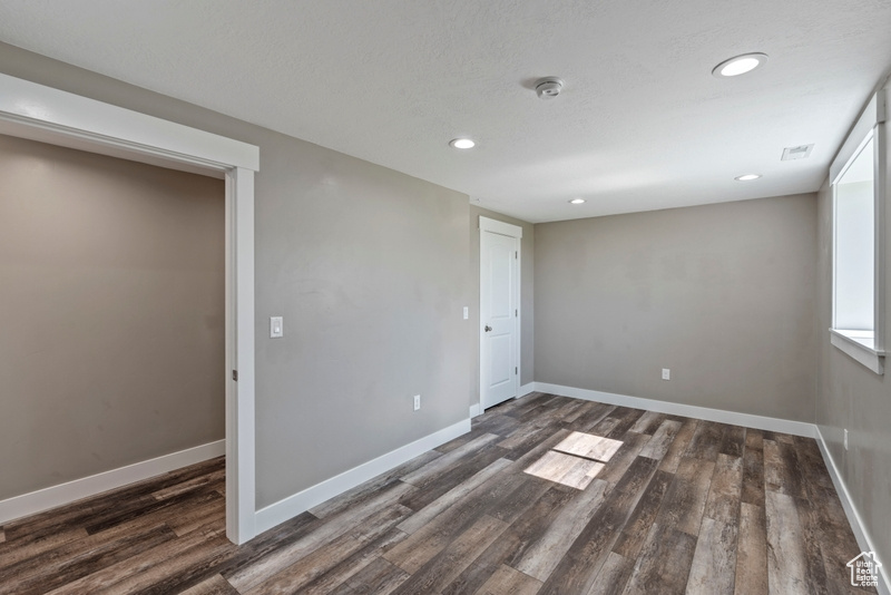 Unfurnished room with a smoke detector, dark wood finished floors, and recessed lighting