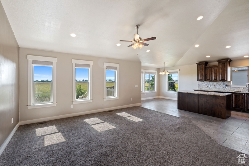 Kitchen with a kitchen island, dark brown cabinets, open floor plan, recessed lighting, and a chandelier