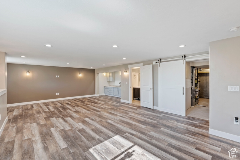 Unfurnished living room with light wood finished floors, recessed lighting, and a barn door