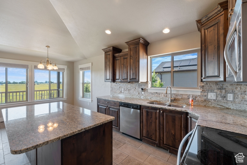 Kitchen with appliances with stainless steel finishes, decorative backsplash, plenty of natural light, a chandelier, and lofted ceiling