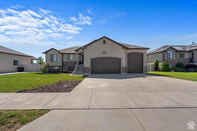 View of front of house with an attached garage, stucco siding, concrete driveway, and stone siding