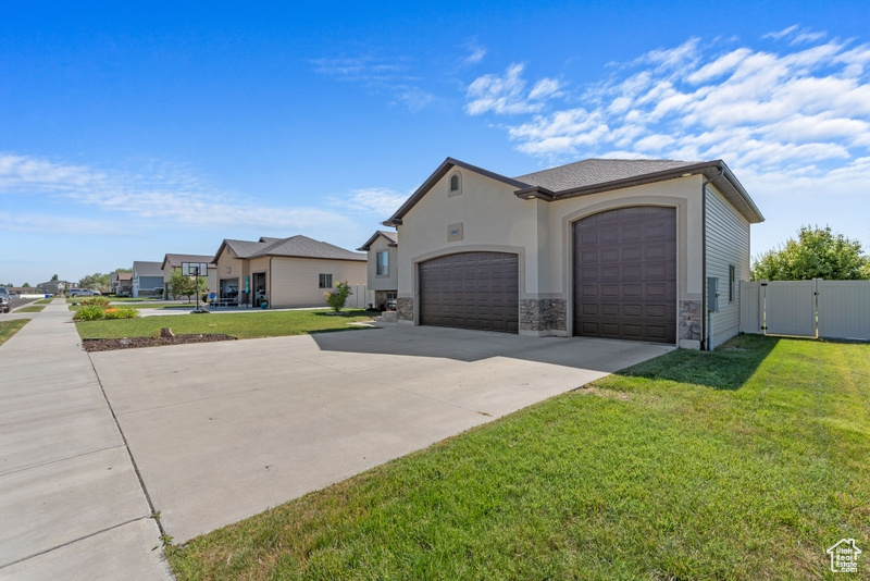 View of property exterior with an attached garage, driveway, stone siding, a gate, and stucco siding