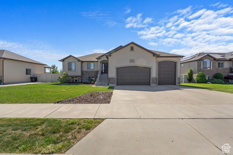 View of front of home with a garage, concrete driveway, stone siding, and stucco siding