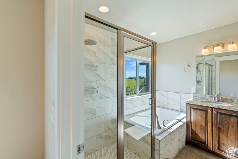 Bathroom with a bath, a shower stall, vanity, and recessed lighting