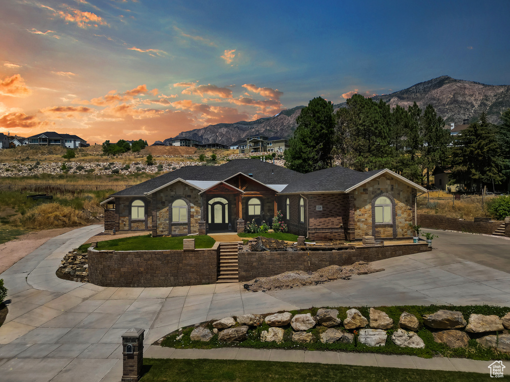 View of front of house featuring a mountain view, stone siding, and curved driveway