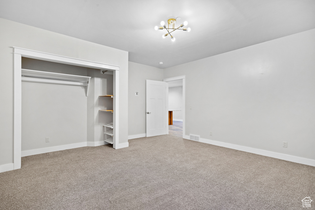 Unfurnished bedroom with carpet, a chandelier, and a closet
