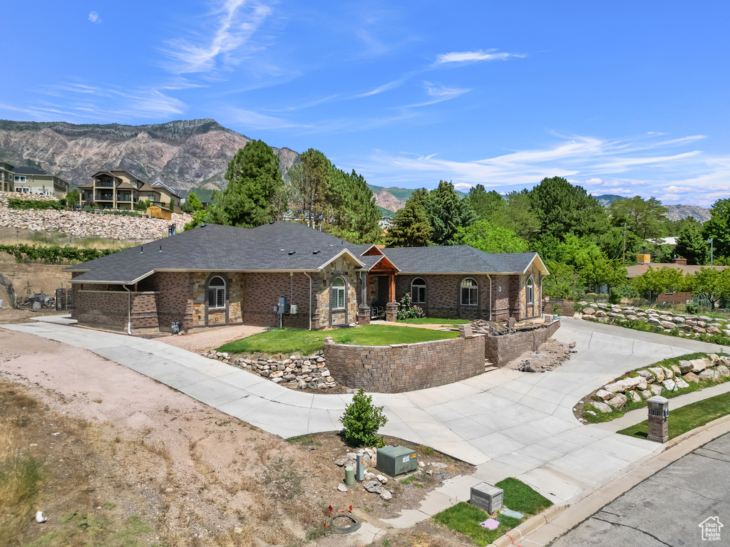 Ranch-style home featuring curved driveway, a mountain view, brick siding, and a shingled roof