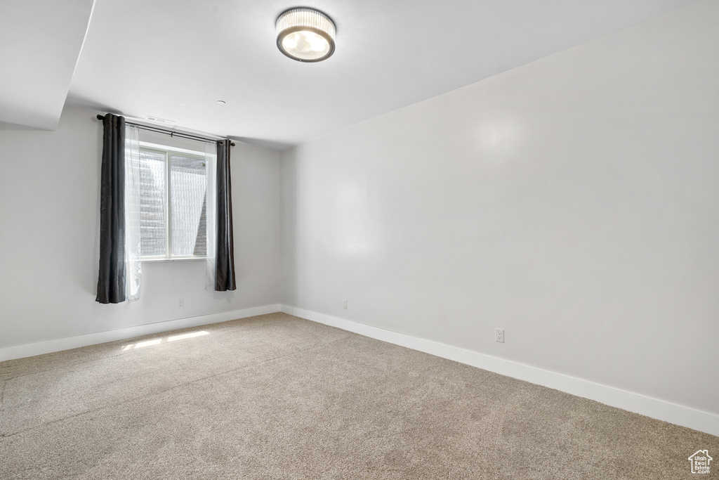 Carpeted spare room featuring baseboards
