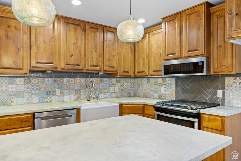 Kitchen with stainless steel appliances, brown cabinetry, light countertops, and recessed lighting