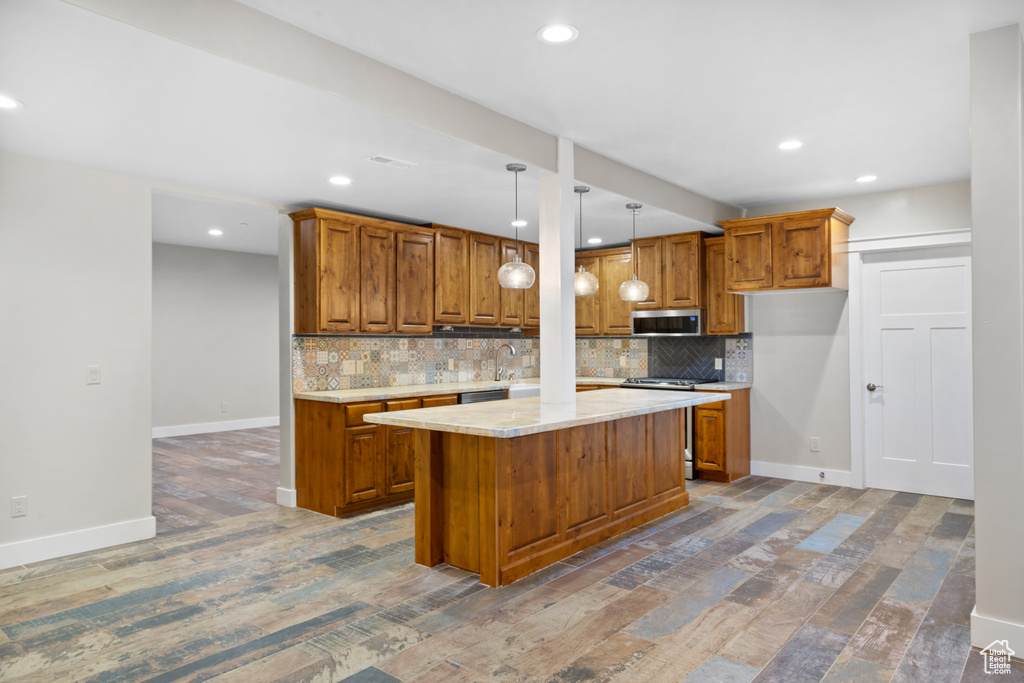 Kitchen featuring appliances with stainless steel finishes, brown cabinetry, tasteful backsplash, and recessed lighting