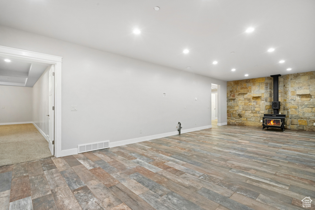 Unfurnished living room featuring a wood stove, wood finished floors, and recessed lighting