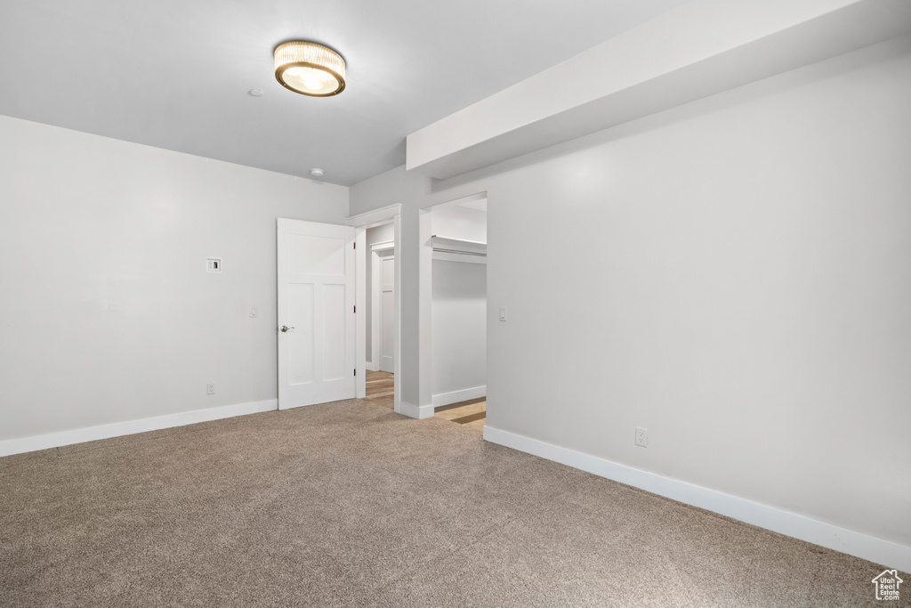 Unfurnished bedroom with light carpet and baseboards