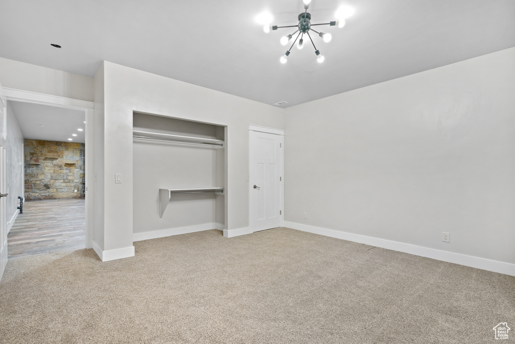 Unfurnished bedroom with a chandelier, carpet, and a closet