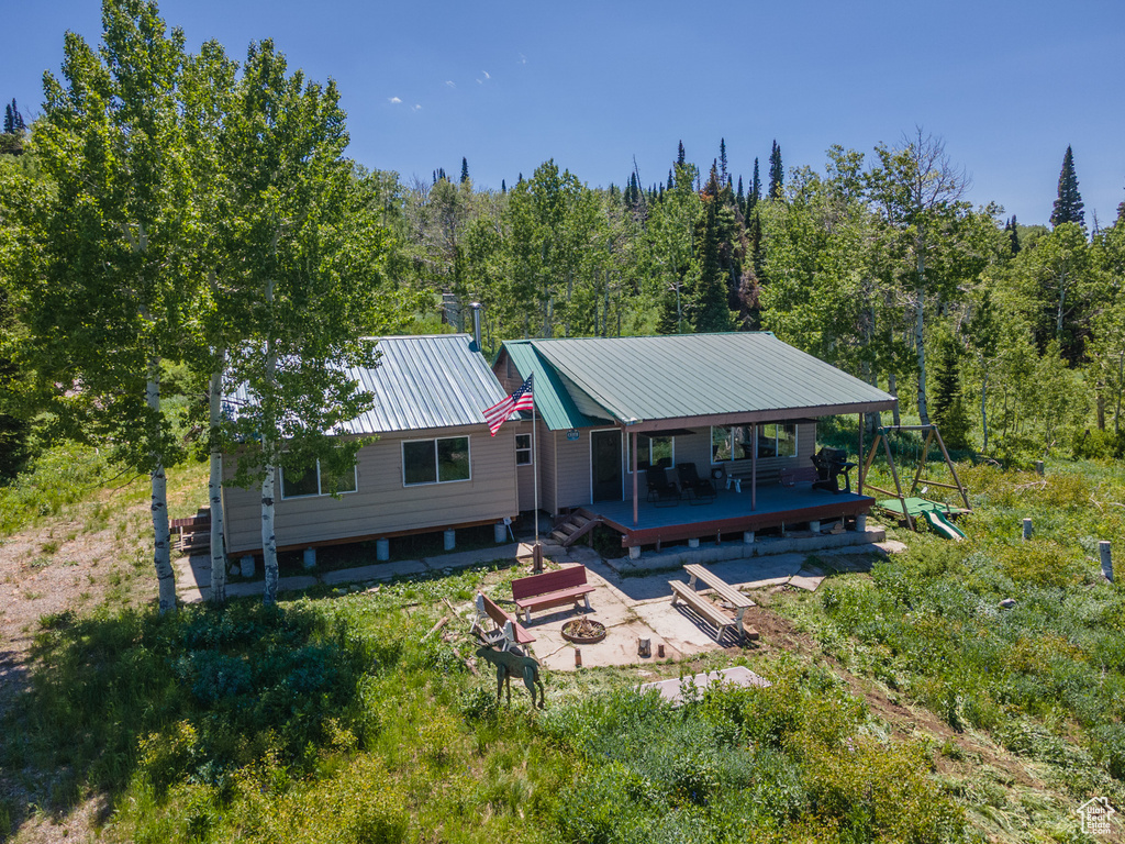 Rear view of house with an outdoor fire pit, a view of trees, a deck, and a metal roof